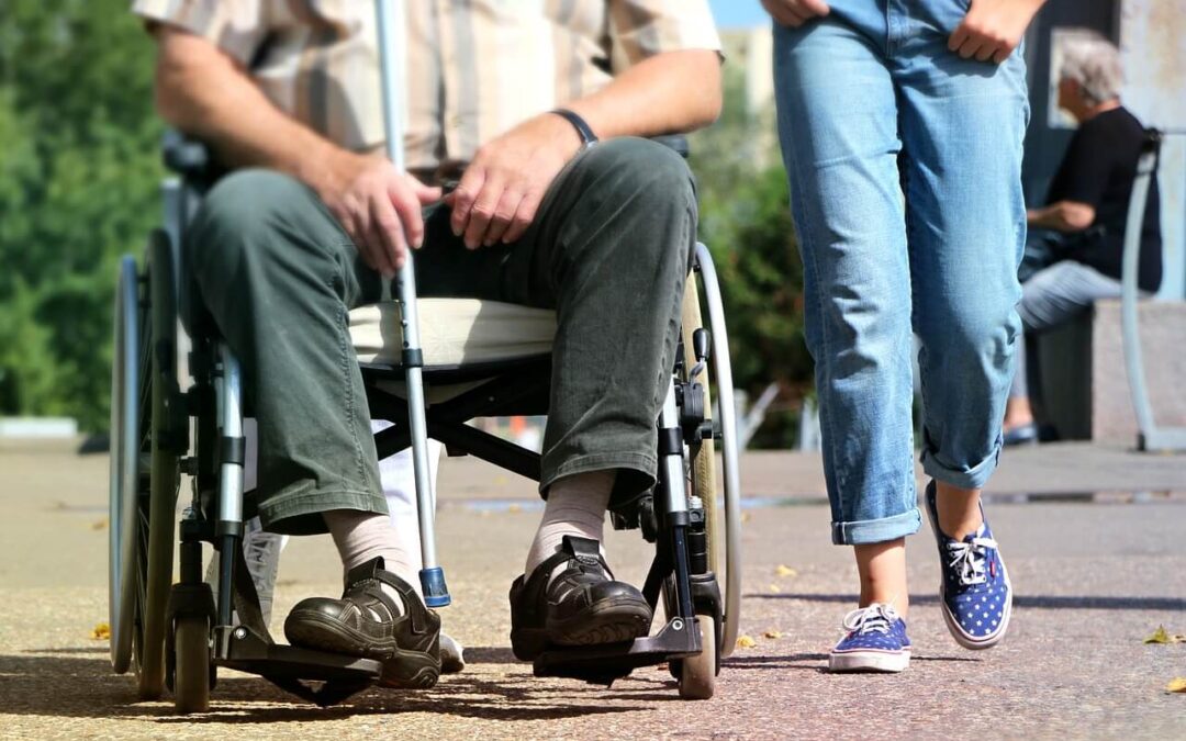 young person walking with an old person in wheelchair